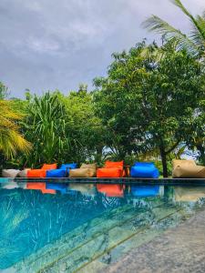 a row of colorful chairs sitting next to a swimming pool at Richards Cabanas in Tissamaharama