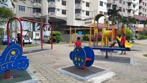 twee kinderen spelen op een speelplaats in een park bij GLORY BEACH RESORT, PD @ Ocean Breeze (seaview) 3 Bedroom Apartment in Port Dickson