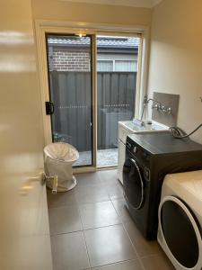 a washing machine in a room with a window at Elegant master bedroom with private bathroom in Point Cook +1 photo