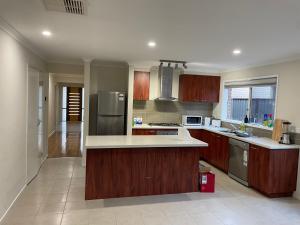 a large kitchen with wooden cabinets and stainless steel appliances at Elegant master bedroom with private bathroom in Point Cook