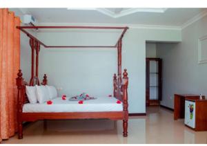 um quarto com uma cama de dossel com flores vermelhas em Taj hotel partnership em Nungwi