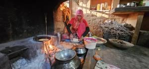 Osiān的住宿－Osian Dhana Ram Ki Dhani Home Stay Osian，站在炉子旁的女人,炉子上放着锅子和锅子