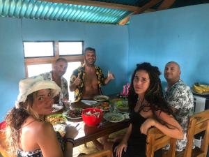 Dua Putri Komodo Homestay في Komodo: مجموعة من الناس يجلسون حول طاولة مع الطعام