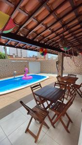 a patio with a table and chairs and a swimming pool at Casa de Férias á 400m pra Praia de Cabo Branco in João Pessoa