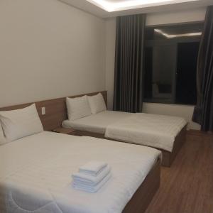 a hotel room with two beds and a window at Khách sạn AN THỊNH 2 in Doc Let