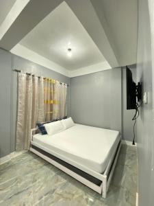 ein weißes Bett in einem Zimmer mit einem TV in der Unterkunft Maicaellas Transient Room in Coron