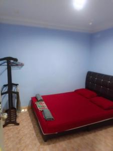Cama roja en habitación con sofá negro en MieHomestay Binjai Rendah, en Bukit Payong