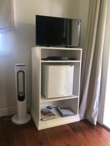 een tv op een witte stand met een luidspreker bij Matamata Historic Cottage- The Wash-House in Matamata