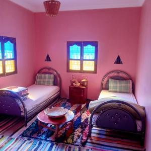 two beds in a room with pink walls and windows at Dar Brahim Resto Beds in Ouarzazate +109 photos