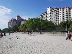 a group of people on a beach with tall buildings at Anneliese suite Glory Beach Resort in Port Dickson