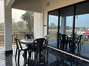 a table and chairs on a balcony with a view of a river at AAHI'S CHILAPATA JUNGLE STAY in Fālākāta