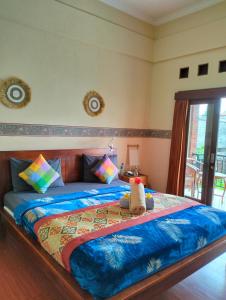 a bedroom with a large bed with a blue comforter at Nami House in Ubud