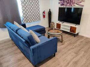 a living room with a blue couch and a tv at Newly Remodeled Cozy 2BR or 3BR Apartment in Tanforan, block away from CalTrain, near SFO in San Bruno