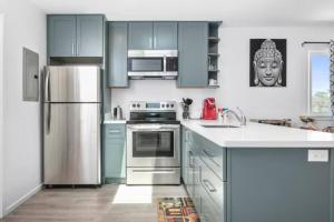 a kitchen with blue cabinets and a stainless steel refrigerator at Newly Remodeled Cozy 2BR or 3BR Apartment in Tanforan, block away from CalTrain, near SFO in San Bruno
