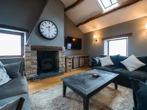 a living room with a clock on the wall at Three Peaks Barn in Carnforth
