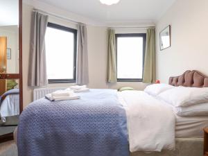 a bedroom with a large white bed with two windows at Harbour Side in Maryport