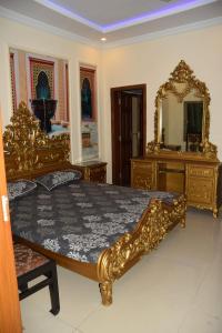 een slaapkamer met een gouden bed en een spiegel bij Haji Jalaluddin Villa in Lower Topa