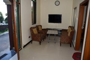 een woonkamer met stoelen en een tafel en een televisie bij Haji Jalaluddin Villa in Lower Topa