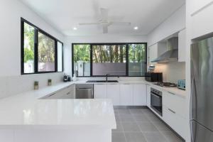 una cocina blanca con armarios blancos y ventanas en Tropic Villa at 2/42 Garrick Street, en Port Douglas