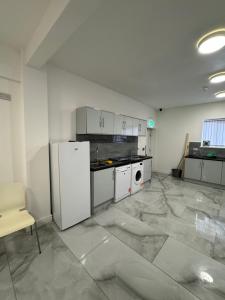 a large kitchen with white appliances in a room at Chief Vic Guest house in Oldham