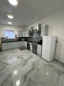 a large kitchen with white cabinets and appliances at Chief Vic Guest house in Oldham