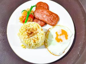 a plate of food with eggs sausage and rice at Juanito's Resort in Tangalan