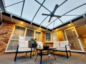 a patio with a glass ceiling with chairs and a table at Cozy Vacation House in Oropi in Oropi