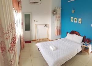 um quarto com uma cama branca e uma parede azul em Ly Tri Ly Son Hotel em Ly Son