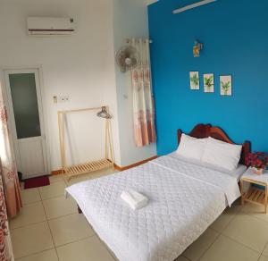 a bedroom with a white bed with a blue wall at Ly Tri Ly Son Hotel in Ly Son