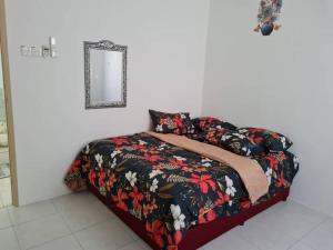 a bed with a flowered blanket and a mirror at Big Homestay For Big Family 2 With Wi fi in Sungai Petani