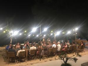 un grupo de personas sentadas en mesas en un escenario por la noche en Life's A Beach en Quy Nhon