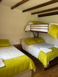 two bunk beds in a room with yellow sheets at Steingarten, Casa de Campo hermosa y amoblada. in Riobamba