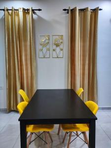 Homestay HABI Residence في Kepala Batas: طاولة سوداء وكراسي صفراء في الغرفة