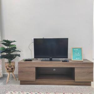 TV en un centro de entretenimiento de madera en una sala de estar en Homestay HABI Residence, en Kepala Batas