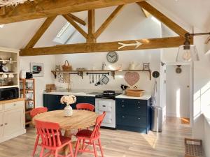 a kitchen with a wooden table and red chairs at The Old Workshop, Wadhurst in Wadhurst