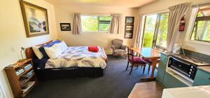 a bedroom with a bed and a desk and a table at Waterwheel Cottage in Upper Moutere