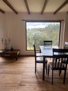 une salle à manger avec une table, des chaises et une grande fenêtre dans l'établissement Steingarten, Casa de Campo hermosa y amoblada., à Riobamba