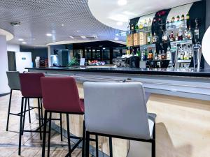 a bar with three chairs and a counter with alcohol at Le Domaine des Fontaines - Expérience in Bernin
