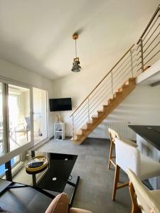 ein Wohnzimmer mit einer Treppe und einem Tisch und Stühlen in der Unterkunft L'Embellie au coeur du village de La Cotinière in La Cotinière