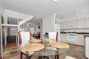 cocina con mesa de cristal y armarios blancos en 2BR Central Montrose Townhome, en Houston