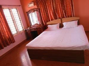 Suman beach House في تشيناي: غرفة نوم بسرير وملاءات بيضاء ونوافذ