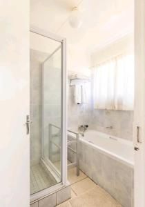 a bathroom with a shower and a bath tub with a mirror at Lovely Linden Cottage with Solar Inverter in Johannesburg