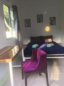 a bedroom with a bed and a purple chair at World Citizen GuestHouse in Koh Phangan