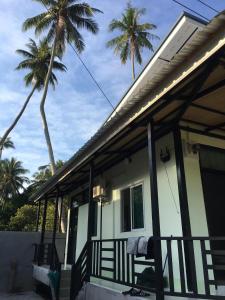 a house with a porch with palm trees in the background at World Citizen GuestHouse in Ko Phangan