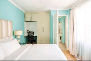 - une chambre avec un lit blanc et un bureau dans l'établissement Lovely Linden Cottage with Solar Inverter, à Johannesbourg