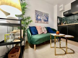 ein Wohnzimmer mit einem grünen Sofa und einem Tisch in der Unterkunft Studio avec parking privé et lave-linge, coeur de Fronton in Fronton