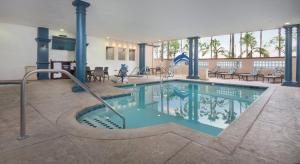 a swimming pool in a hotel with tables and chairs at Peacock Suites in Anaheim