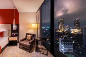 Cette chambre comprend un lit, un bureau et une fenêtre. dans l'établissement Mövenpick Hotel Colombo, à Colombo