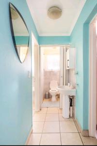 a bathroom with a toilet and a sink and a mirror at Lovely Linden Cottage with Solar Inverter in Johannesburg