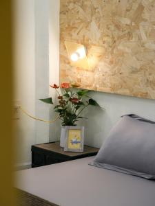 1 dormitorio con 1 cama y un jarrón de flores sobre una mesa en Vit-xiem Room - Double room - Duck Homestay Ben Tre, en Ấp Phú Lợi